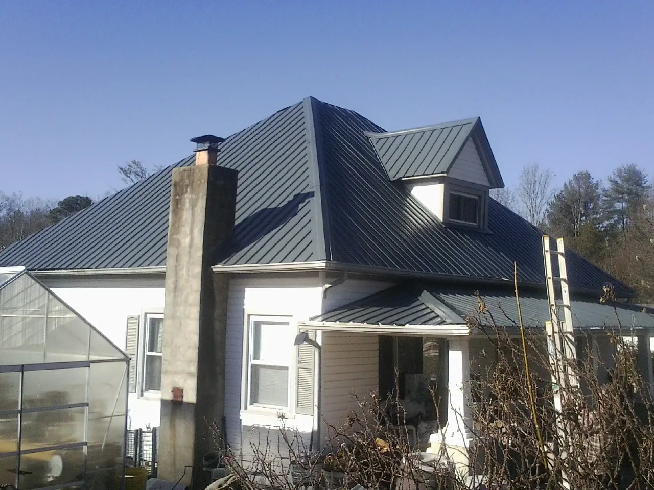 Dark blue standing seam metal roof on a white farmhouse with dormer — Slate & Tile Roof Repair by Roofing Brothers in Cairo
