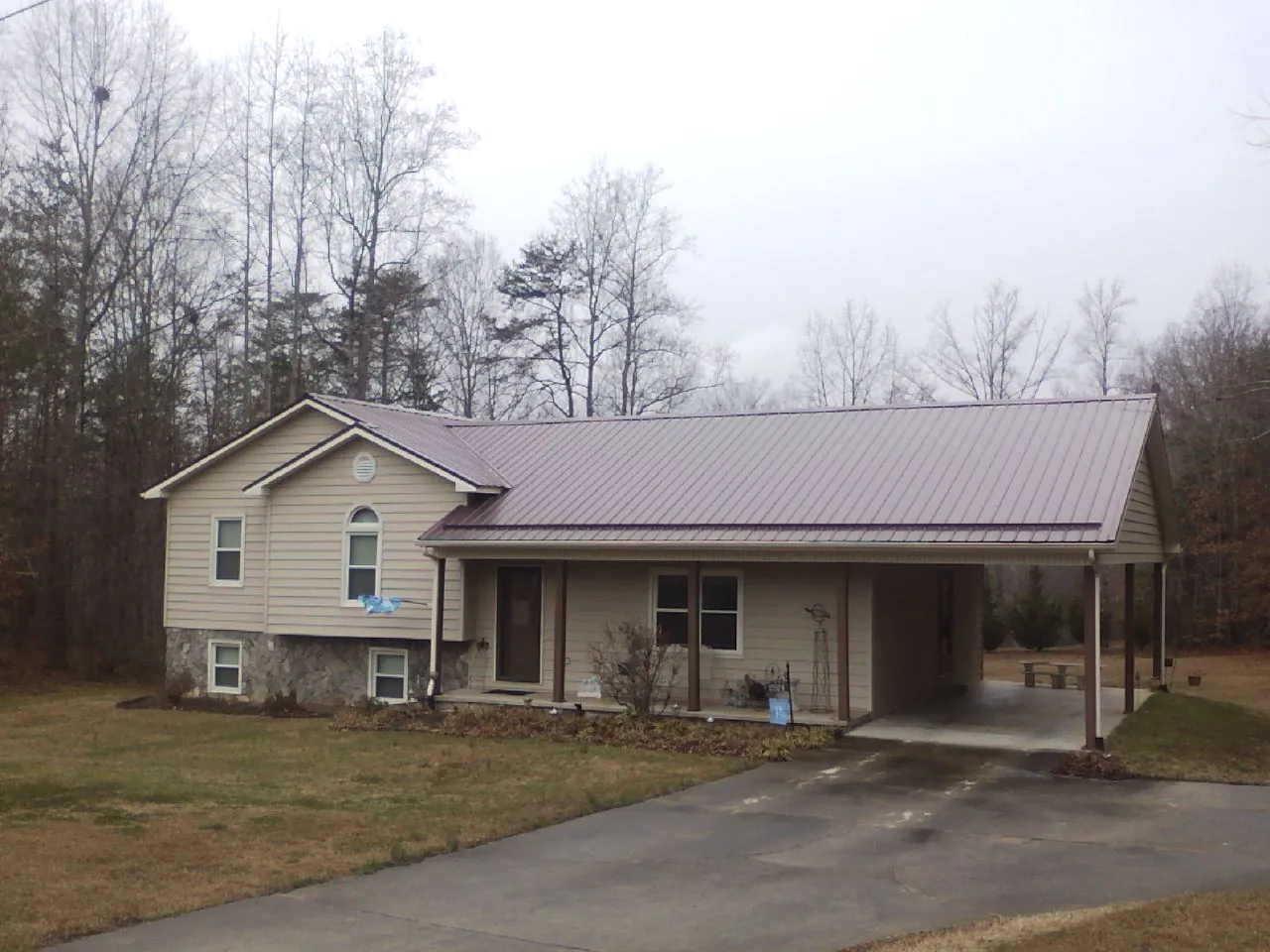 Burgundy metal roof on a tan split level home with an attached carport in Cairo