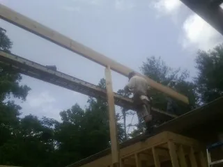 Carpenter setting a ridge beam over a new addition frame — Ice Dam Removal by Roofing Brothers in Cairo