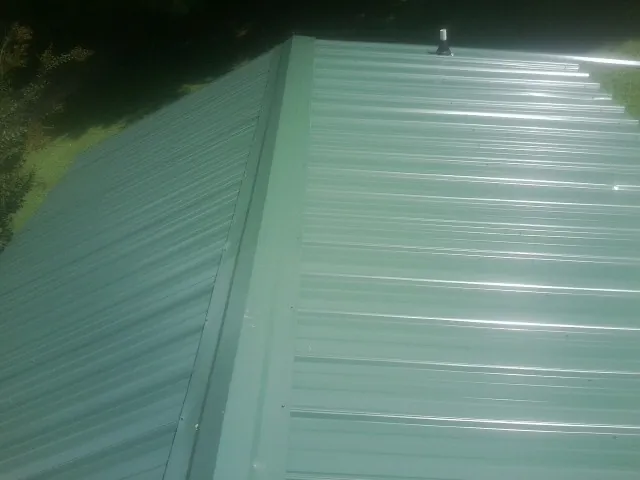 New green metal panels meeting at the ridge of a roof — Flat Roof Repair work by our crew in Cairo