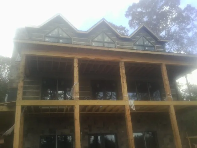 Dormers and porch framing on a large log home under construction — Roof Coating work by our crew in Cairo