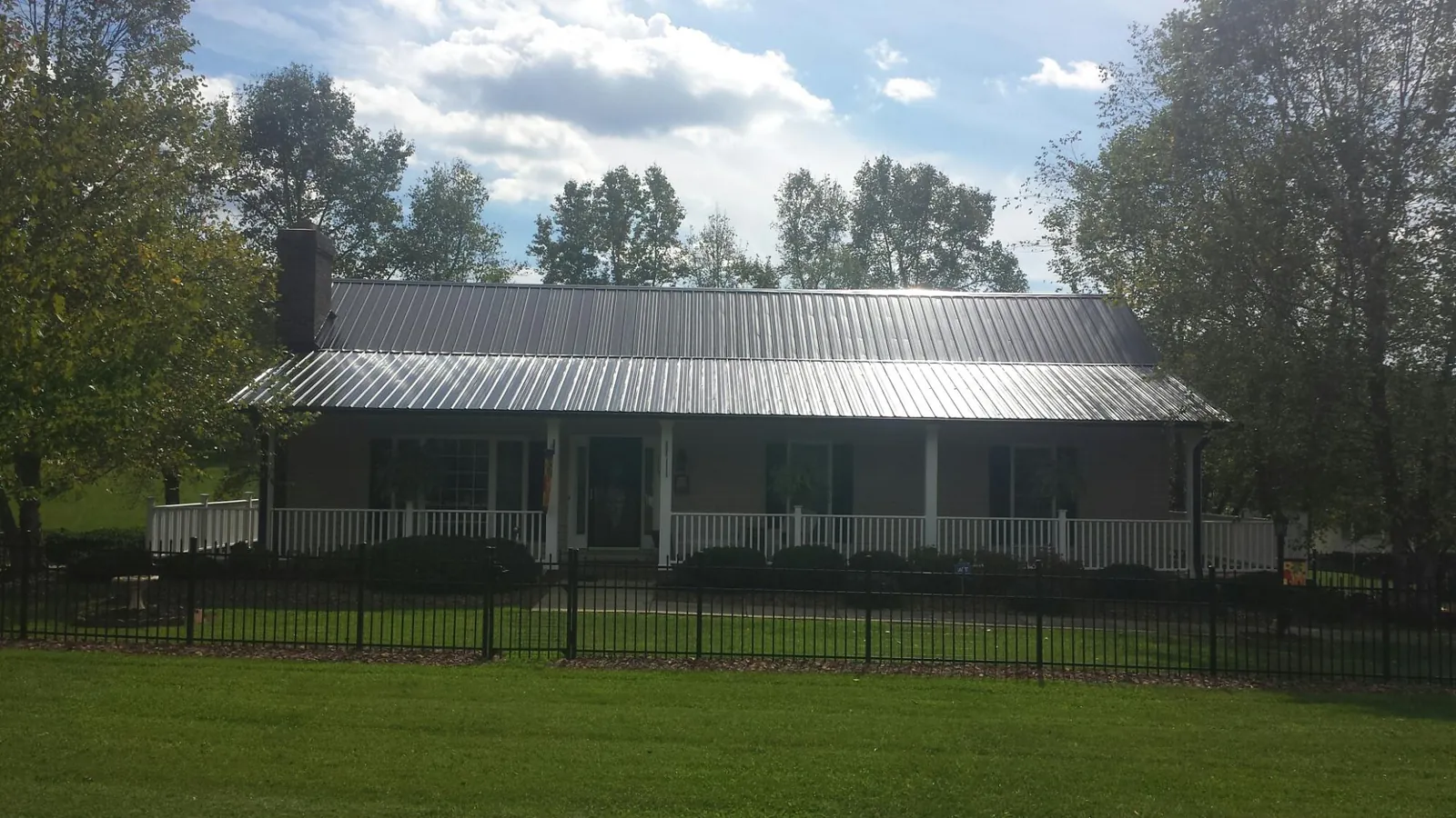Gray metal roof on a brick ranch with a full width front porch — Gutter Guard Installation work by our crew in Cairo