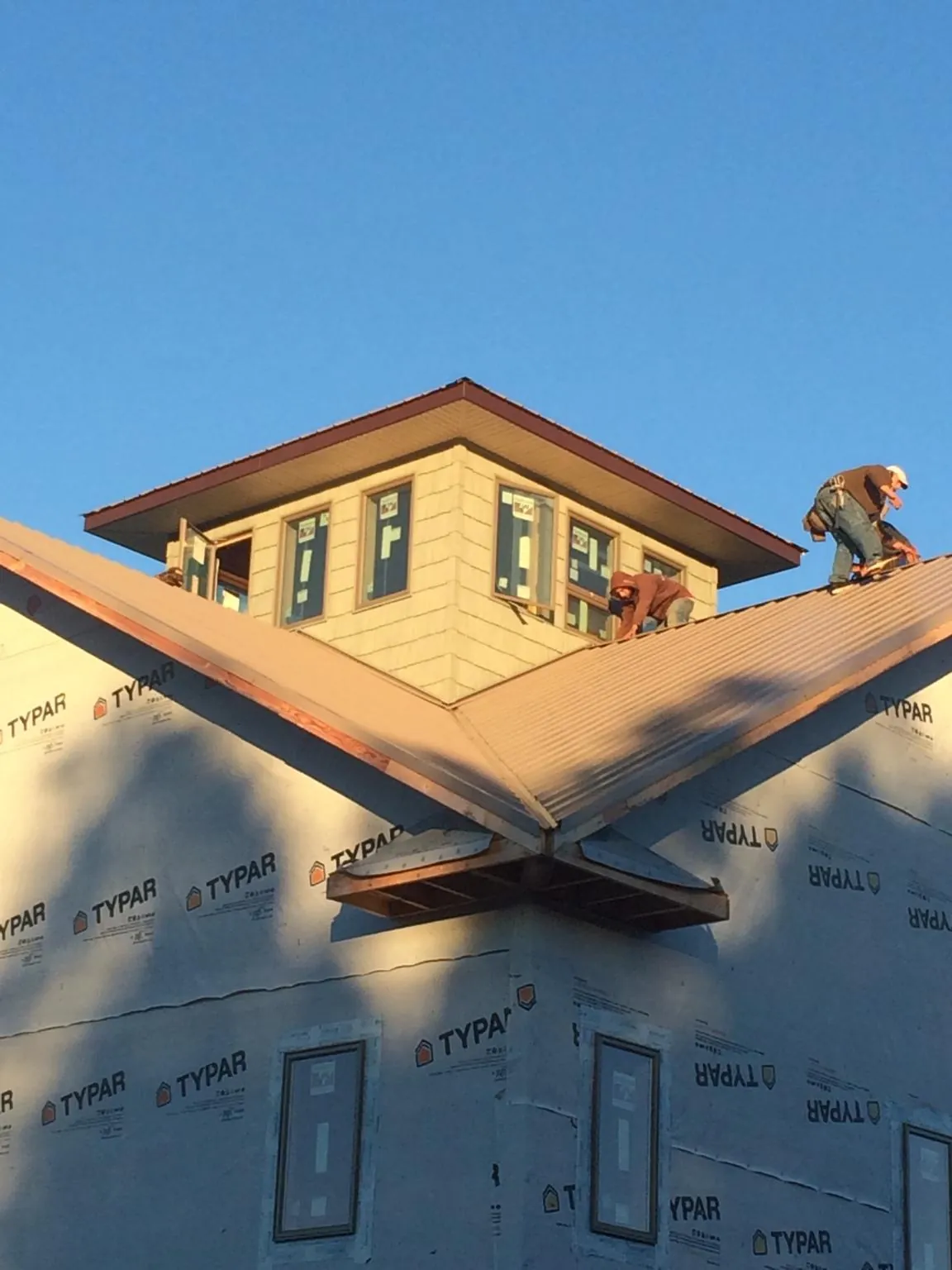 Roofers working around a rooftop cupola on a new metal roof at sunset — Roof Waterproofing in Cairo by Roofing Brothers